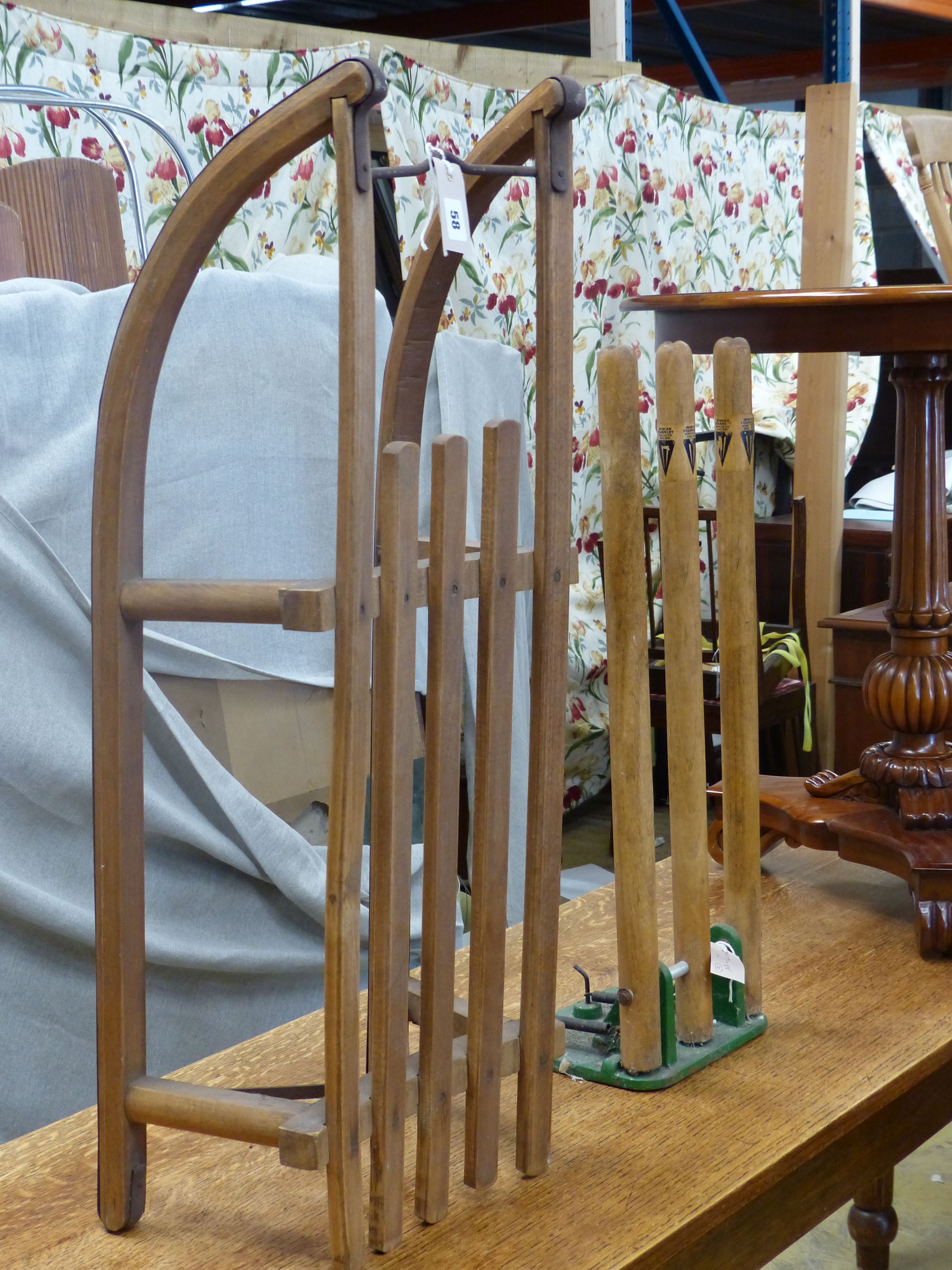 A vintage sled, a set of practise cricket stumps on sprung cast iron base